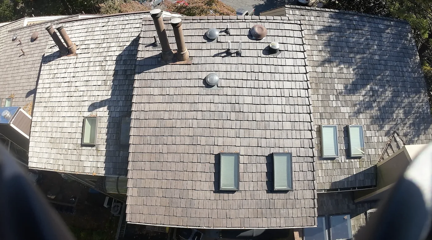 Weathered cedar shake roof with skylights, vents and flues