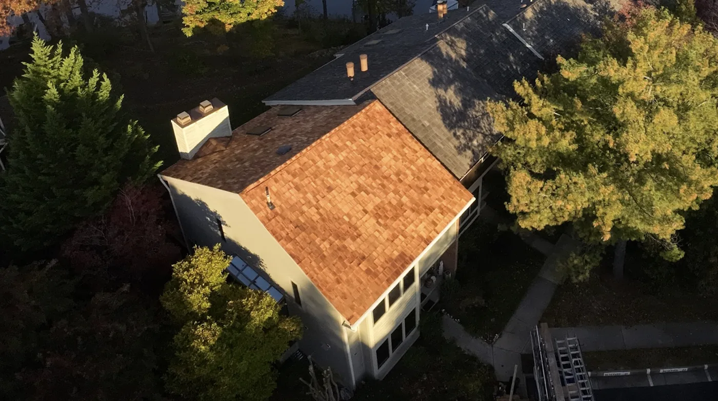 New cedar shakes beside an existing shingle roof, with chimneys and skylights