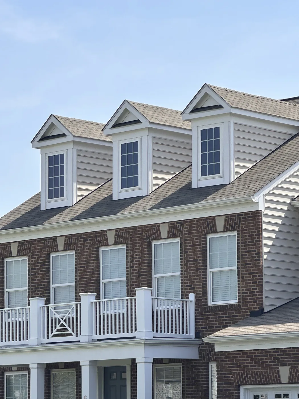 Shingle roof around three dormers on a brick colonial