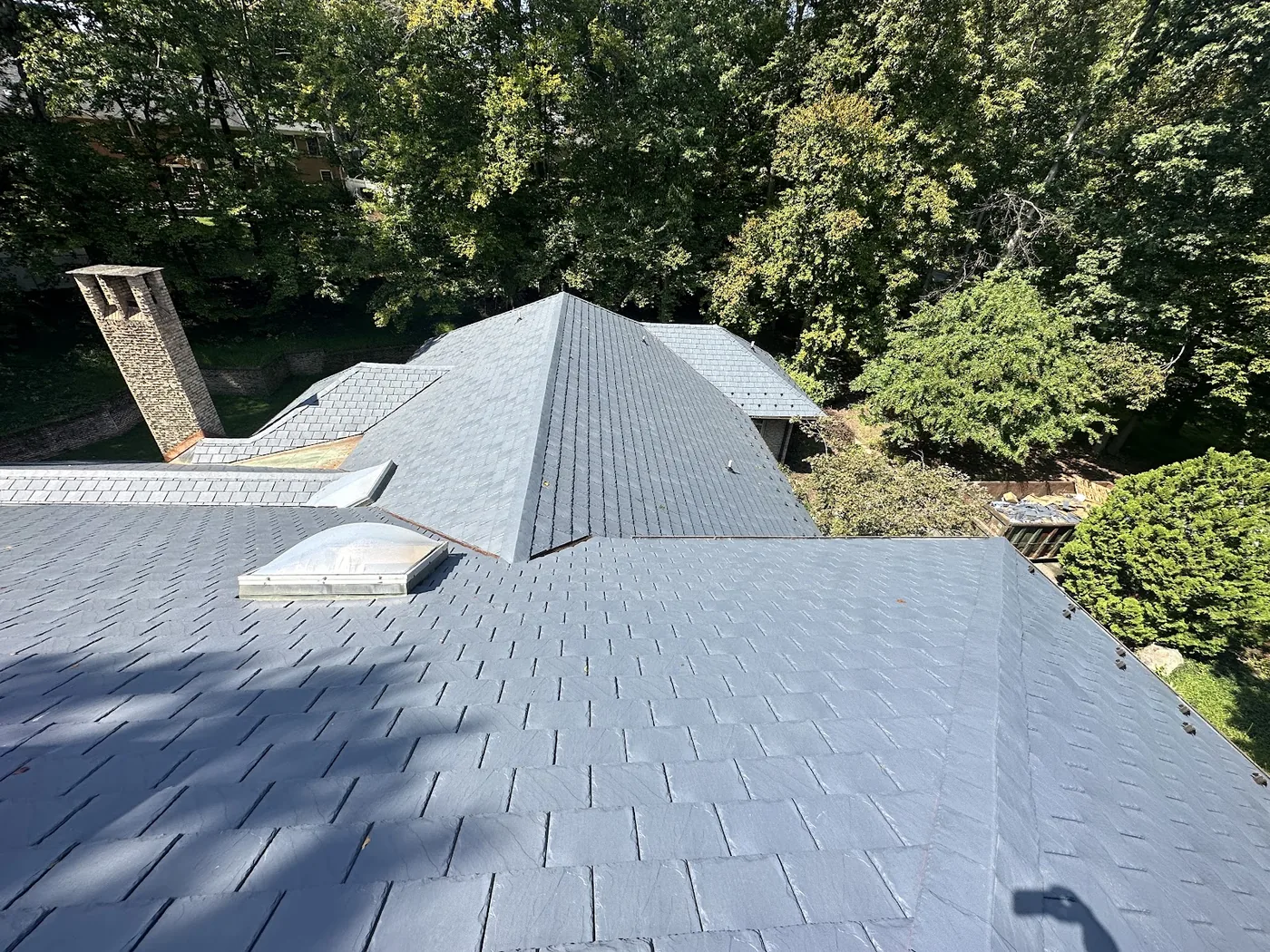 Slate-style roof around a skylight and a brick chimney