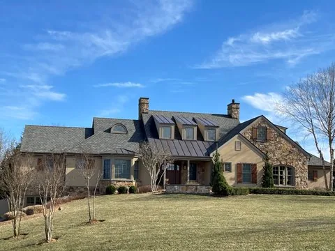 Standing seam metal roof sections over an entry on a stone and stucco house