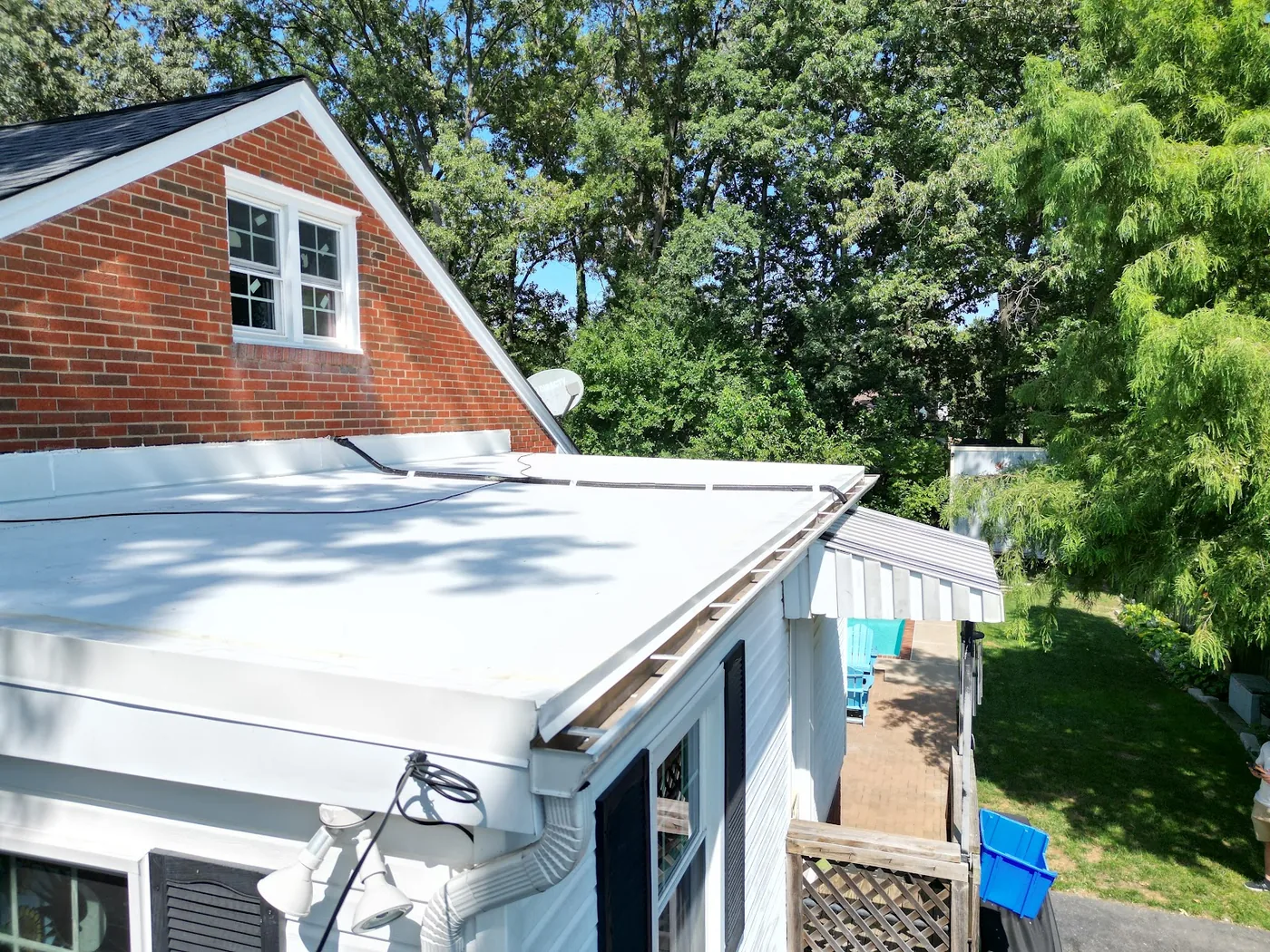 White low-slope membrane roof on a rear addition, with metal edge and gutter