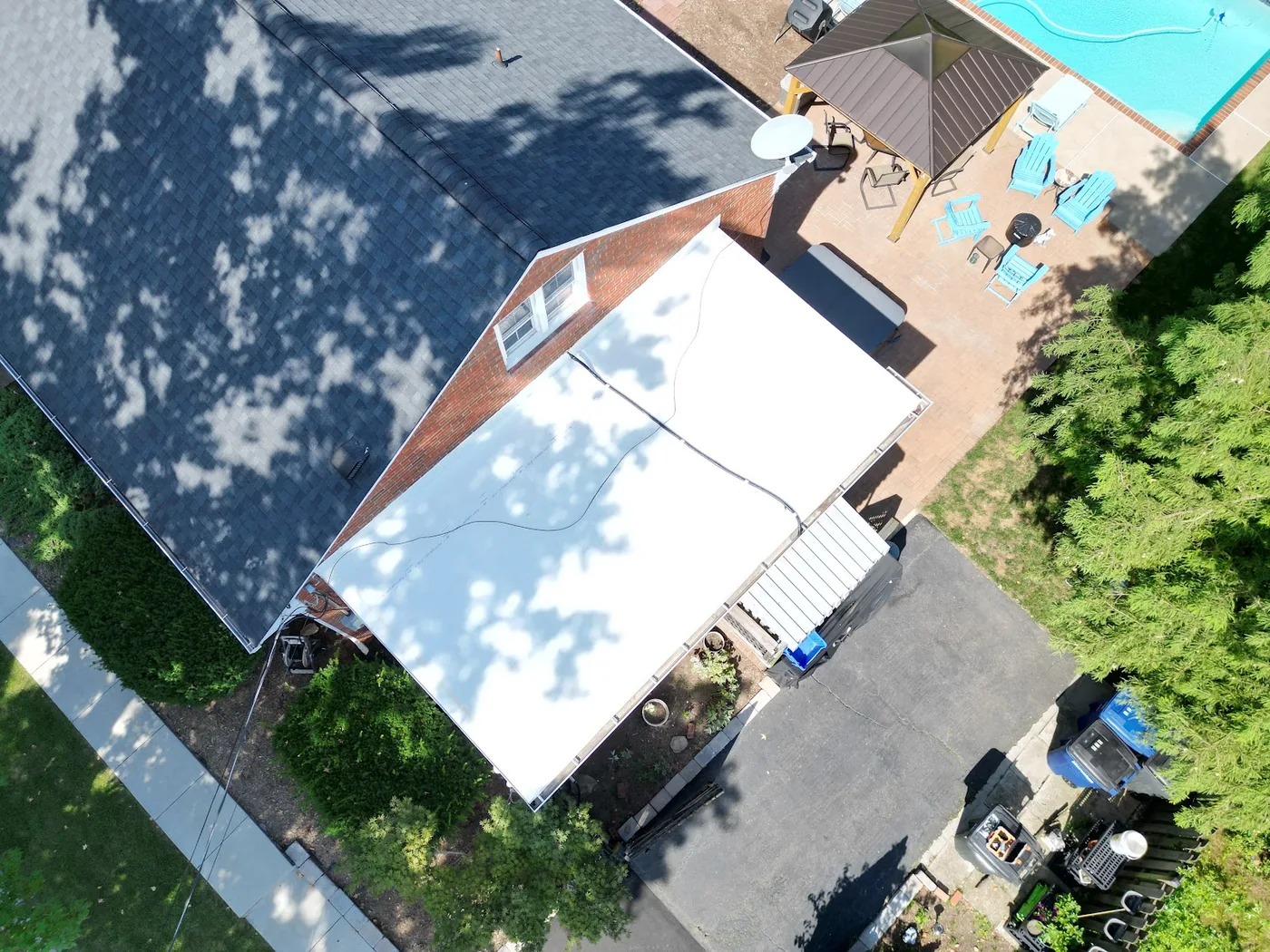 Aerial view of a white low-slope roof beside a shingle roof
